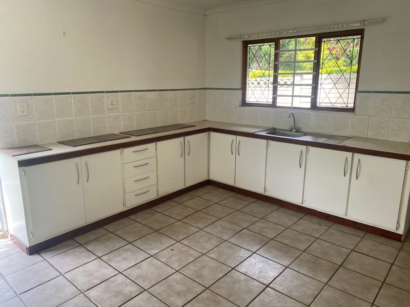 A functional, empty kitchen featuring white cabinetry, tiled splashbacks, and tiled flooring, offering a blank canvas for potential modern updates.