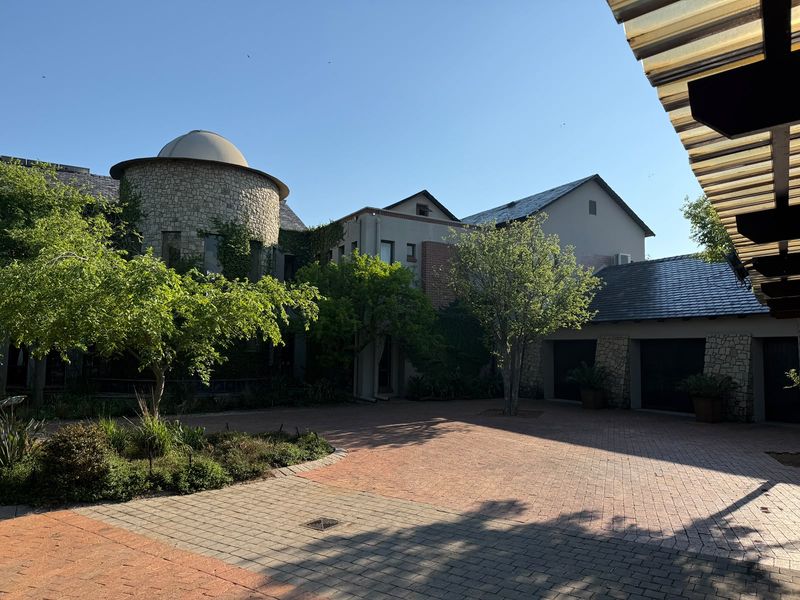 A spacious front courtyard featuring a unique stone-clad domed architectural element, paved driveway, and integrated garage access within a well-maintained residential property.