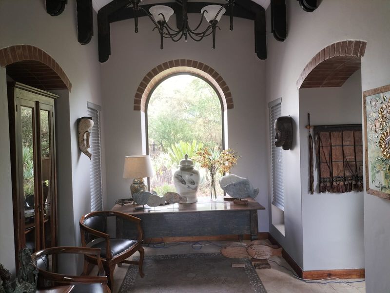 A characterful living space featuring exposed timber ceiling beams, an elegant arched window with brick detailing, and neutral tiled flooring.