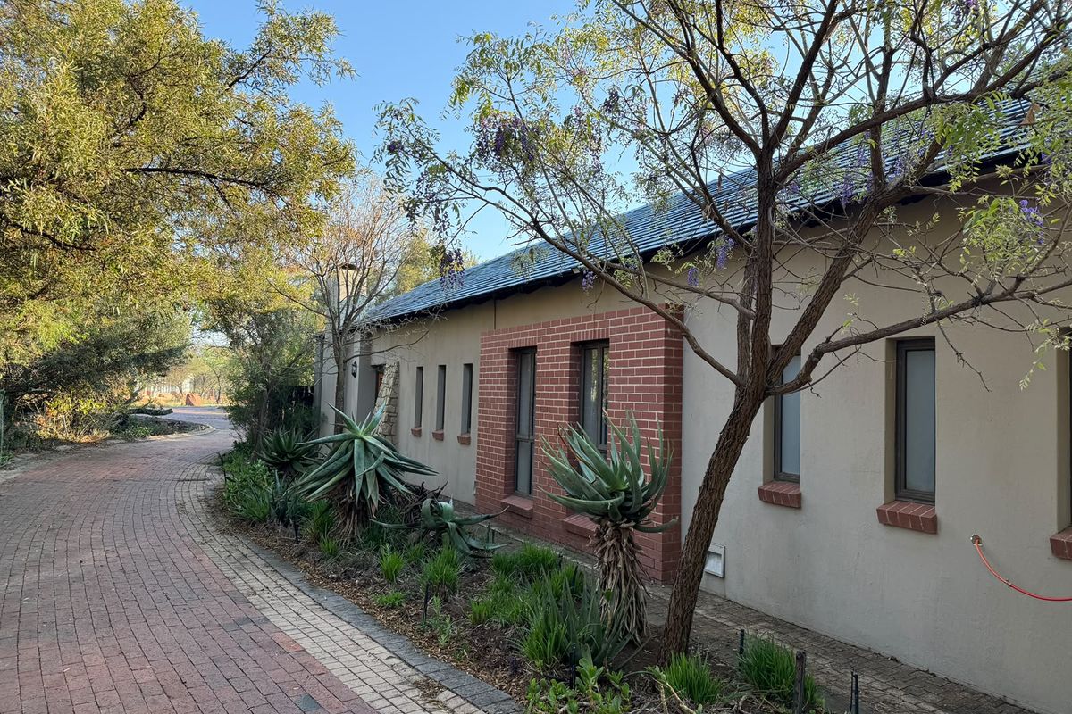 A side view of the property featuring a brick paved walkway, landscaped garden beds, and a well-maintained exterior facade with brick accents.