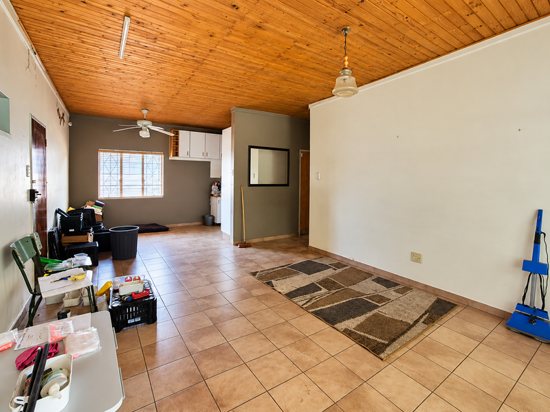 Open plan living area featuring a timber ceiling, tiled flooring, and a small kitchen nook, offering a versatile space for renovation and modernization.