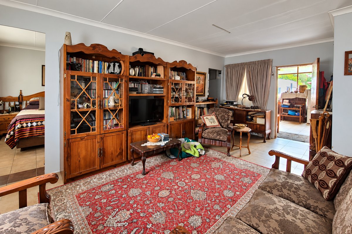 A spacious living room featuring tiled flooring and built-in wooden cabinetry, with direct access to an outdoor area through a sliding door.