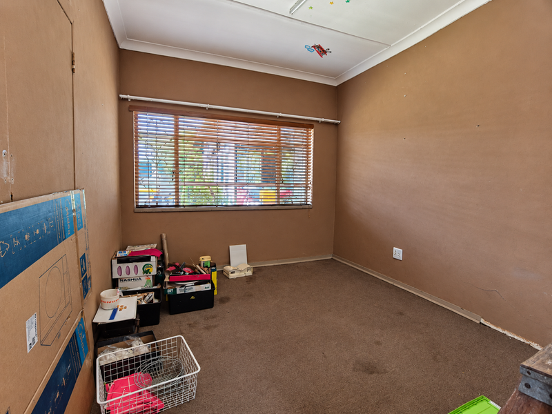 A vacant bedroom featuring brown carpet flooring, neutral wall tones, and venetian blinds, offering a blank canvas for renovation or restyling.