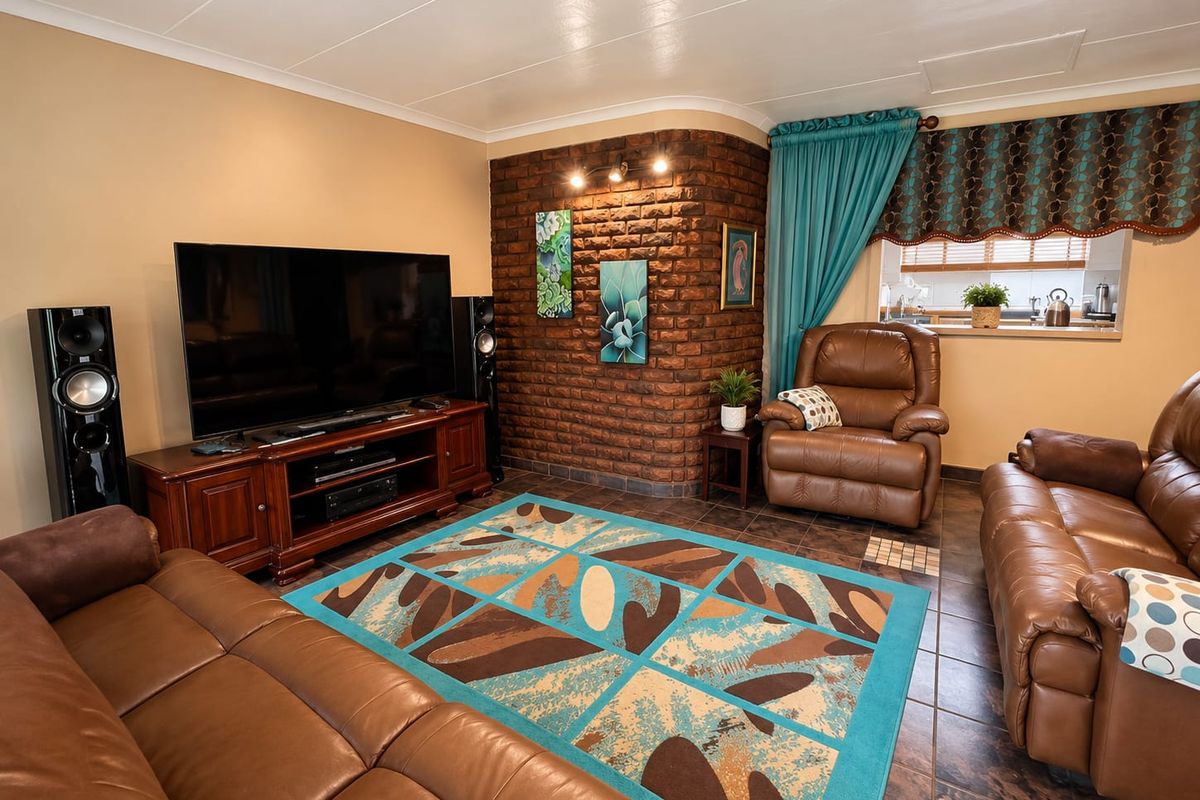 A cozy living room featuring an exposed brick accent wall, tiled flooring, and a convenient pass-through window connecting to the kitchen area.