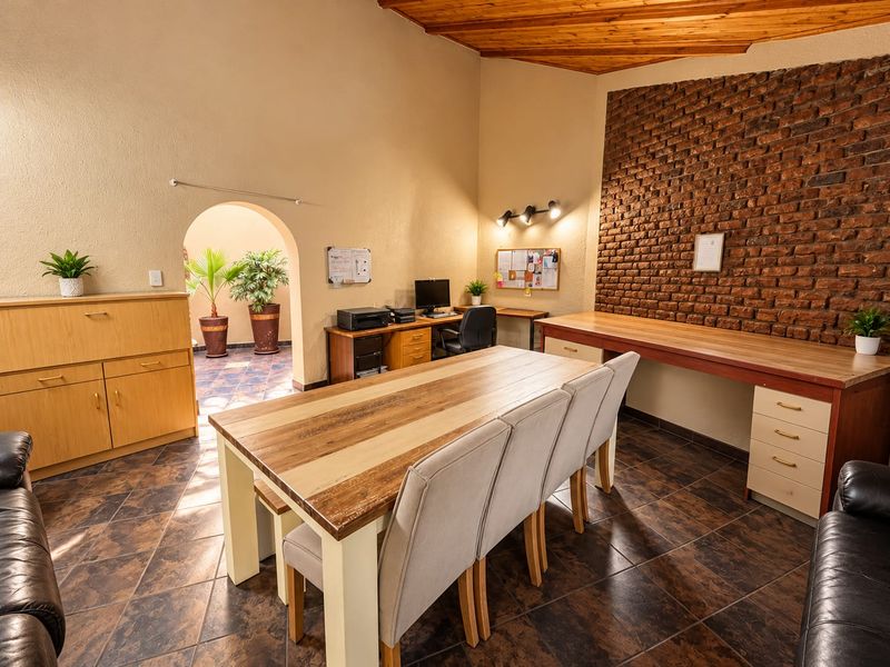 Spacious living area featuring a striking exposed brick wall, timber vaulted ceiling, tiled flooring, and integrated built-in desk and cabinetry.
