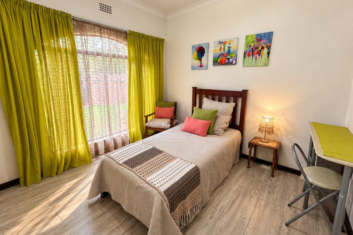 A bright and well-maintained bedroom featuring wood-look tile flooring, an arched window with natural light, and classic cove cornice detailing.