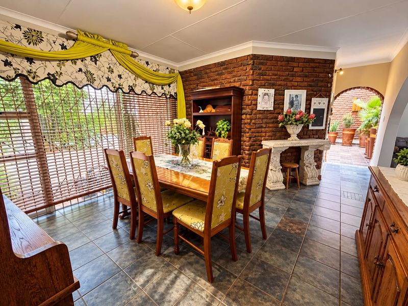 A dining room featuring an exposed brick feature wall, tiled flooring, and a sliding glass door leading to an outdoor area.