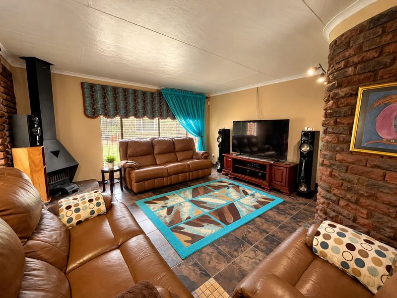 Spacious living room featuring a prominent exposed brick fireplace, a modern freestanding metal fireplace, and durable tiled flooring.