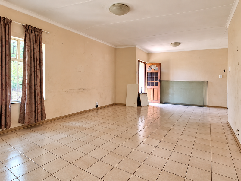 A spacious, empty living area featuring tiled flooring and neutral walls, offering a blank canvas for renovation or interior design updates.