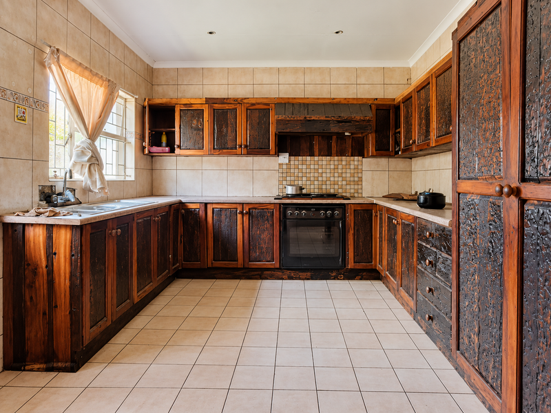 A functional kitchen featuring extensive built-in wooden cabinetry, tiled flooring, a built-in oven, and a double sink with a tiled backsplash.