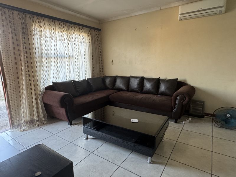 A living room featuring ceramic floor tiles, a wall-mounted air conditioning unit, and a sliding glass door leading to the exterior.