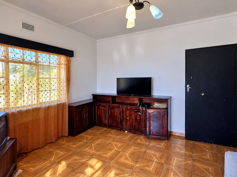 A living room featuring tiled flooring, a ceiling light fixture, and a window with natural light.