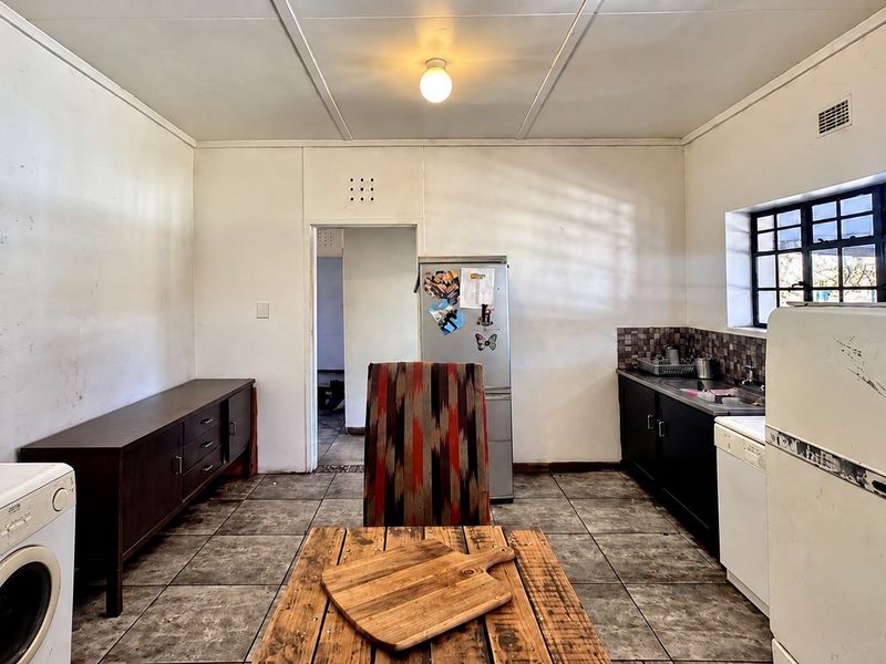 A functional kitchen space featuring tiled flooring, built-in cabinetry, and a tiled backsplash, offering potential for modernization and cosmetic updates.