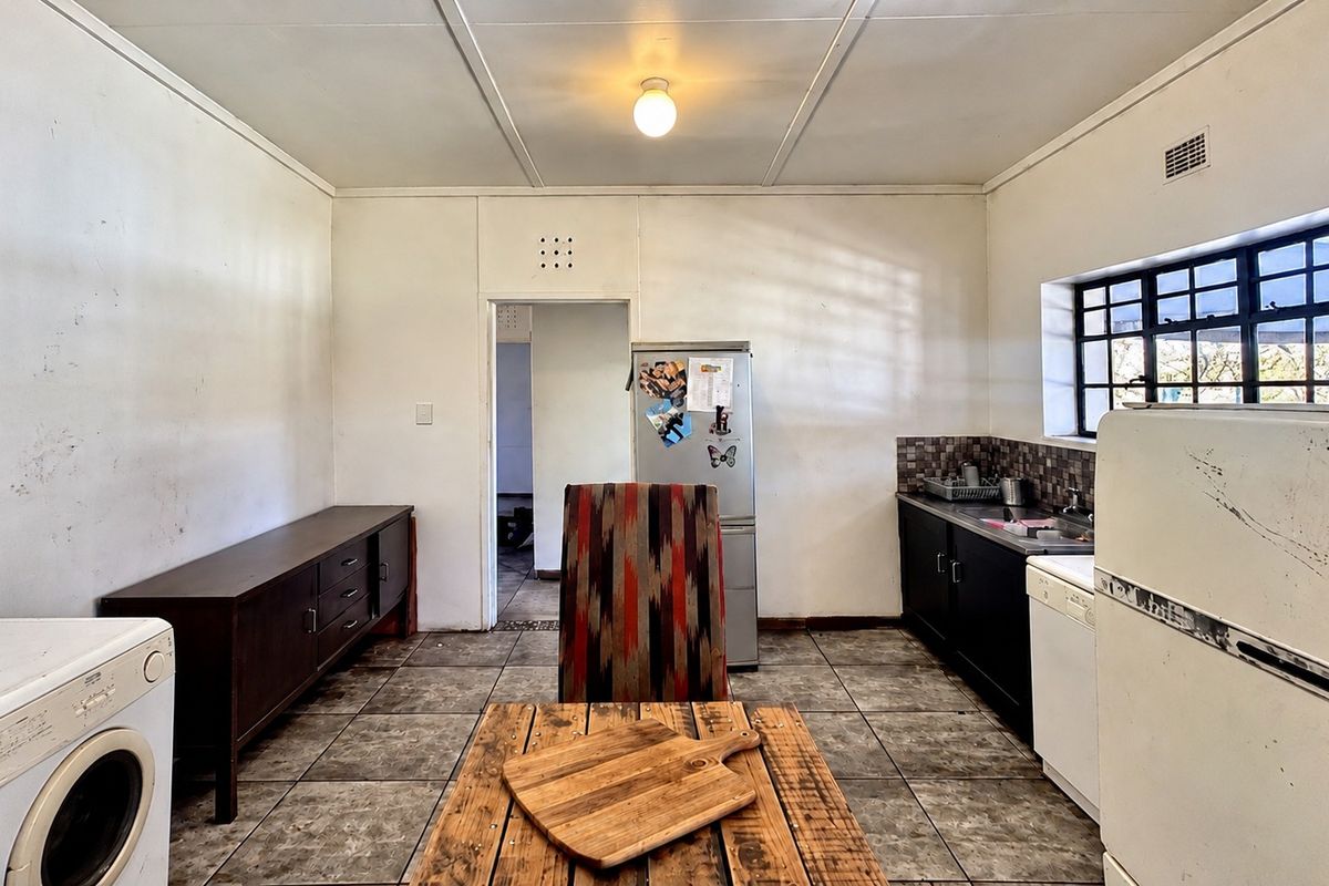 A functional kitchen space featuring tiled flooring, built-in cabinetry, and a tiled backsplash, offering potential for modernization and cosmetic updates.