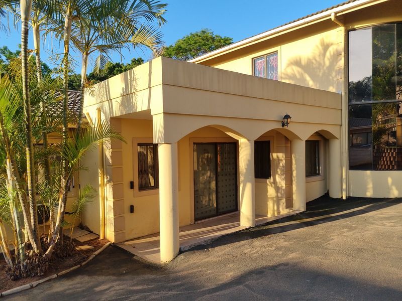 Front entrance featuring a covered arched portico with concrete columns, tiled porch area, and sliding glass door access.