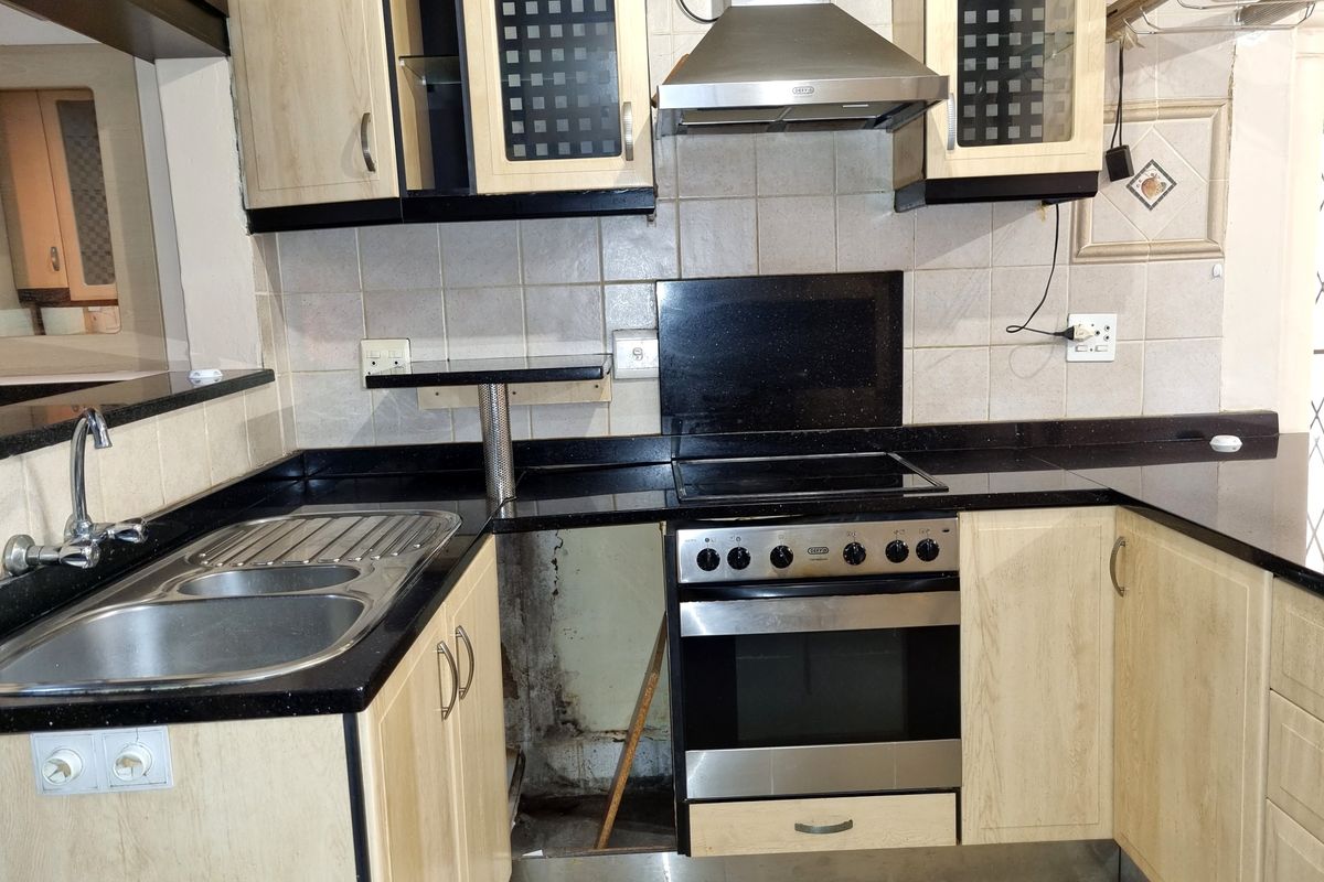 Kitchen featuring granite countertops, built-in oven, and extractor fan. Note the missing lower cabinet panel and visible wall damage requiring repair.