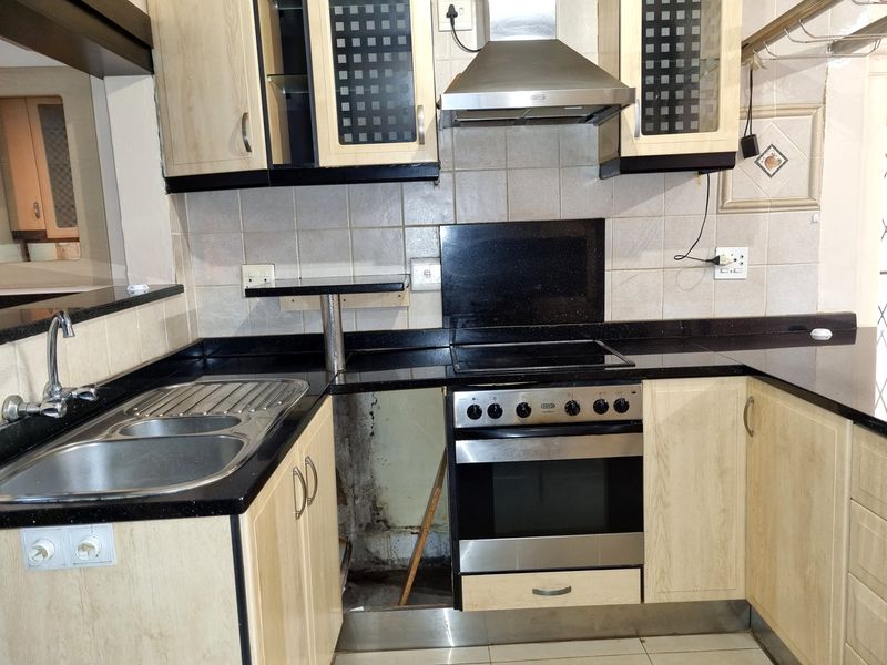 Kitchen featuring granite countertops, built-in oven, and extractor fan. Note the missing lower cabinet panel and visible wall damage requiring repair.