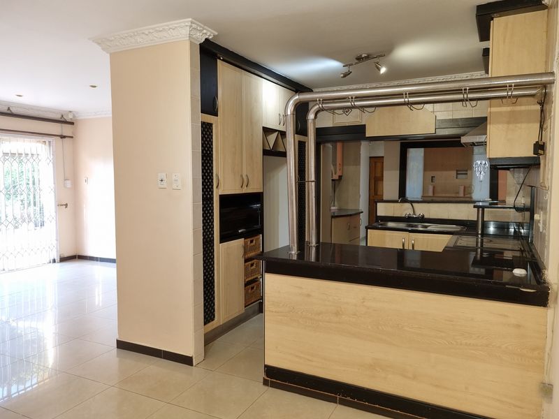 Spacious kitchen featuring light wood cabinetry, black granite countertops, a breakfast bar, and tiled flooring, offering a functional layout with ample storage space.