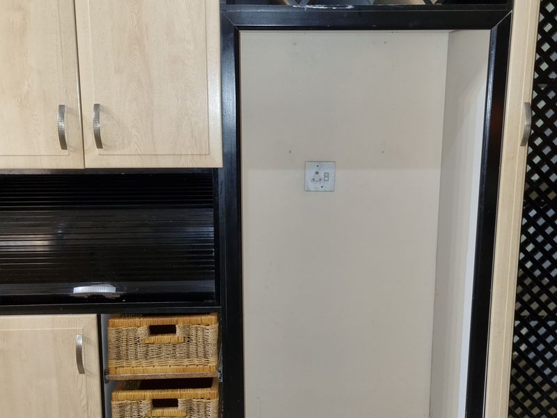 A kitchen storage unit featuring built-in cabinetry, a dedicated wine rack, and a recessed alcove for an appliance with an integrated electrical outlet.