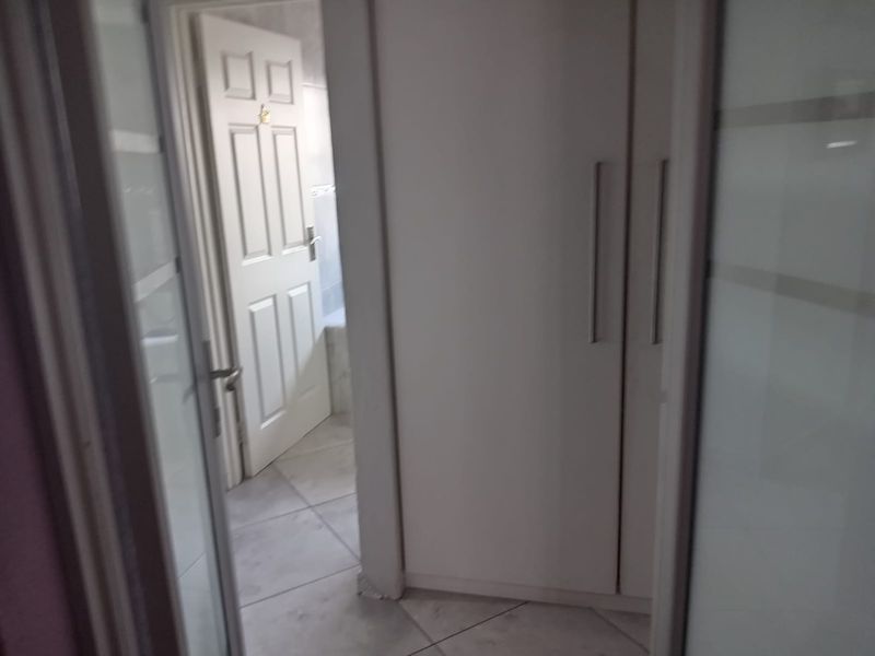 A functional hallway area featuring built-in cupboards and tiled flooring, providing access to adjacent rooms.