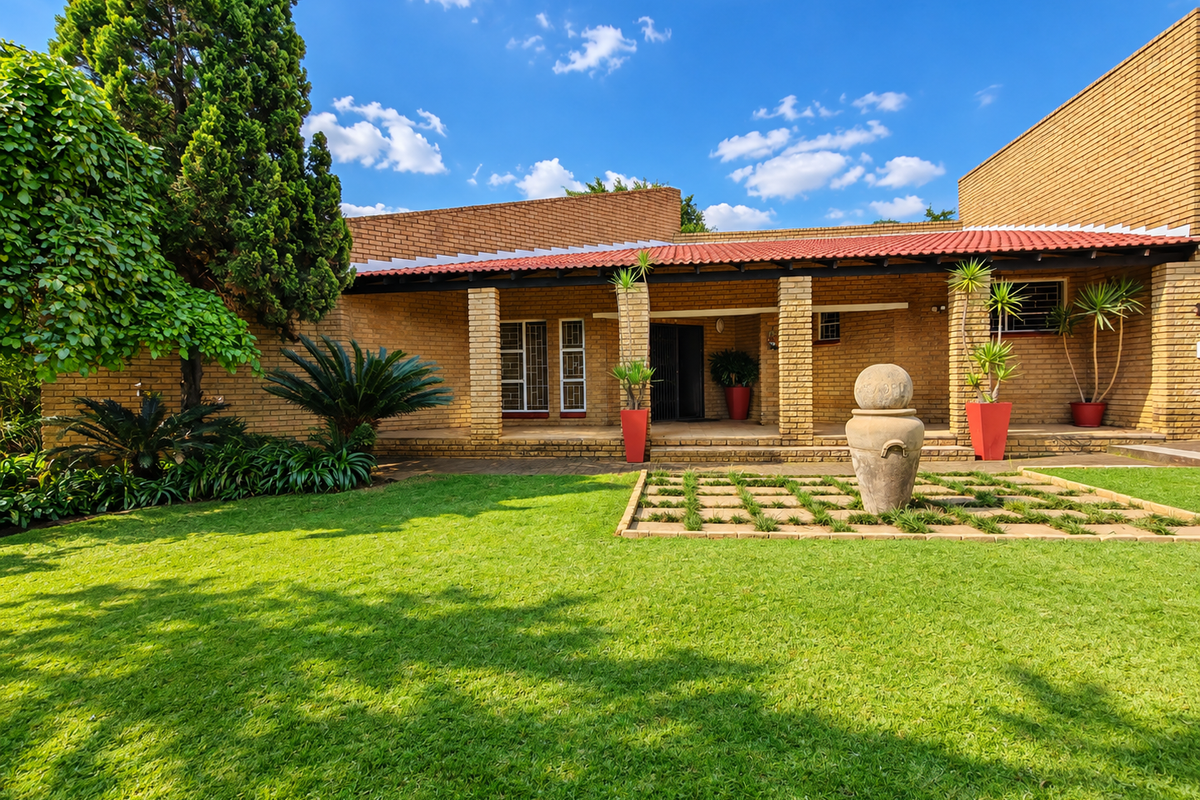 A well-maintained rear exterior view featuring a brick facade, a covered patio area with brick pillars, and a neatly landscaped garden.