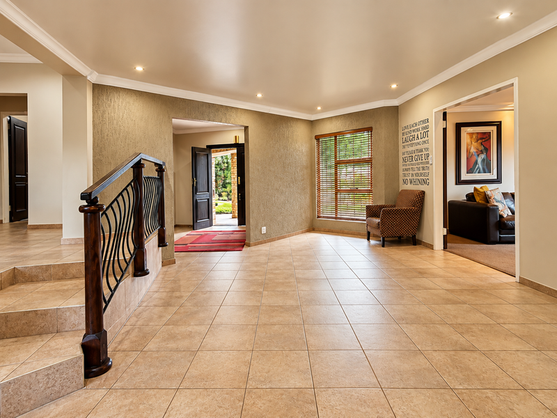 Spacious entrance hall featuring tiled flooring, a decorative wrought iron balustrade, and recessed lighting, providing a welcoming transition between living areas.