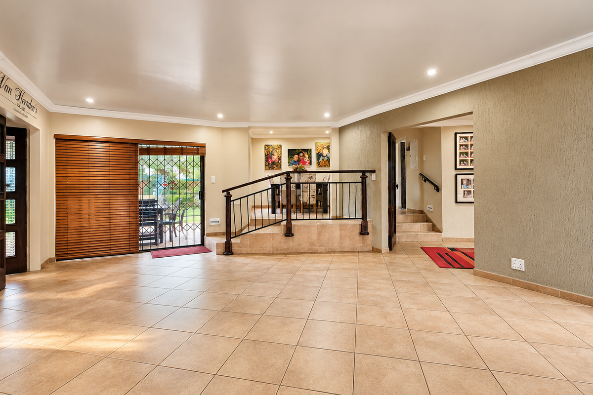 Spacious open-plan living area featuring ceramic tile flooring, recessed lighting, and a raised dining platform with a decorative metal railing.