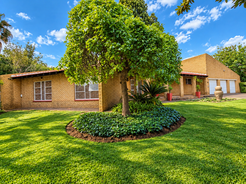 A well-maintained single-story face brick house featuring a triple garage, secure window bars, and a lush, manicured front garden.