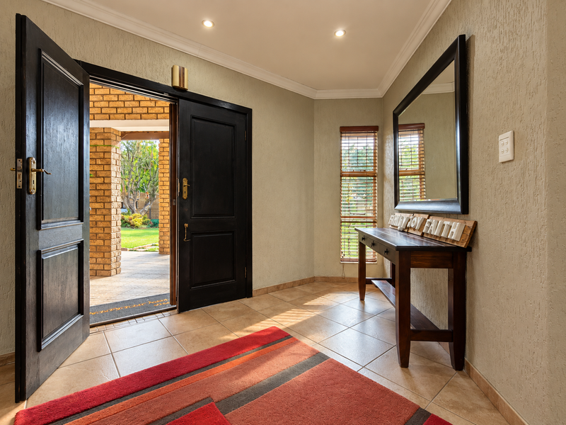 A welcoming entrance hall featuring tiled flooring, textured walls, recessed lighting, and double doors opening onto a covered patio area.