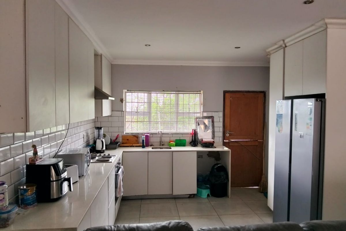 A functional kitchen featuring white cabinetry, subway tile backsplash, quartz countertops, and integrated appliances, with direct access to an exterior door.