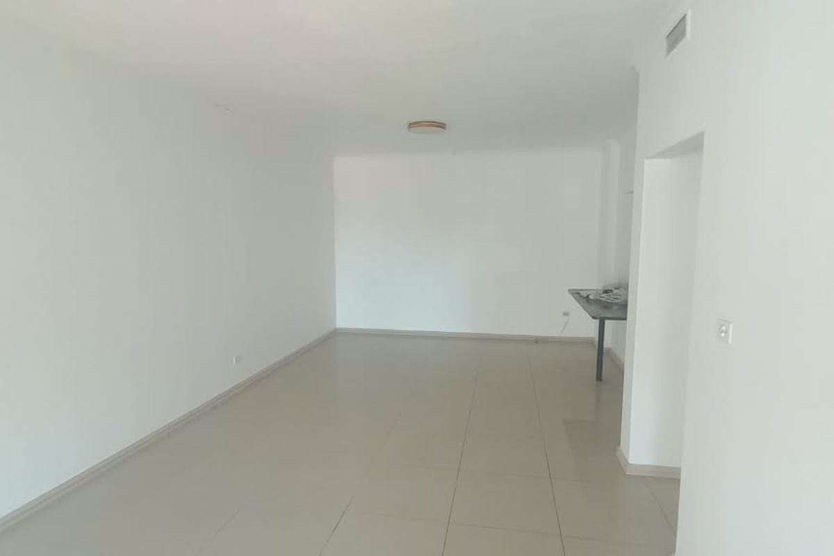 A bright, empty living area featuring neutral tiled flooring, recessed ceiling lighting, and an integrated air conditioning vent.