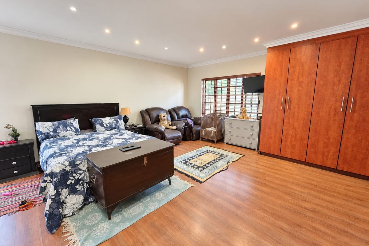 Spacious bedroom featuring laminate flooring, recessed downlighting, and extensive built-in wooden cupboards providing ample storage space.