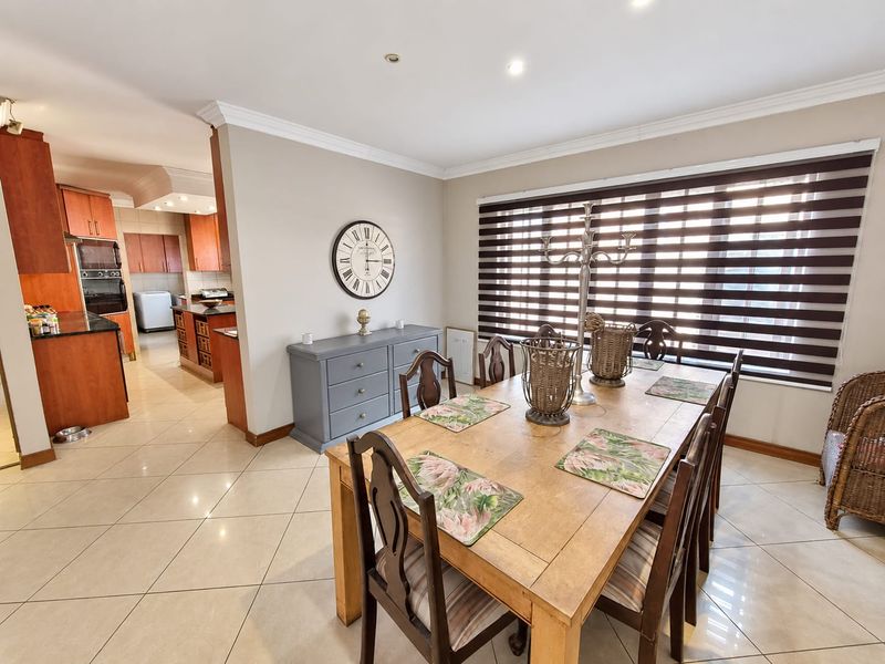 Open-plan dining area featuring tiled flooring and recessed lighting, seamlessly flowing into a well-appointed kitchen with granite countertops and built-in cabinetry.