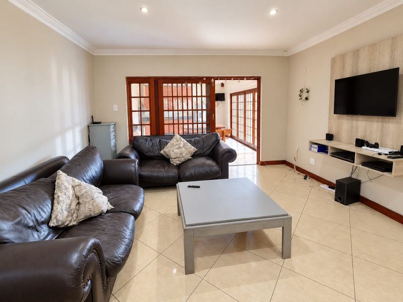 Spacious living room featuring tiled flooring, recessed lighting, and a built-in media console, with direct access to an outdoor patio area.