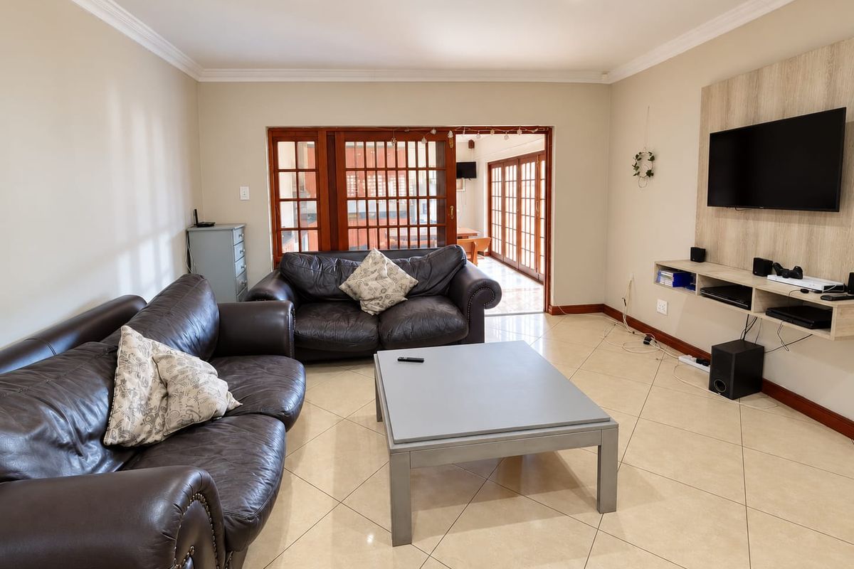 Spacious living room featuring tiled flooring, recessed lighting, and a built-in media console, with direct access to an outdoor patio area.