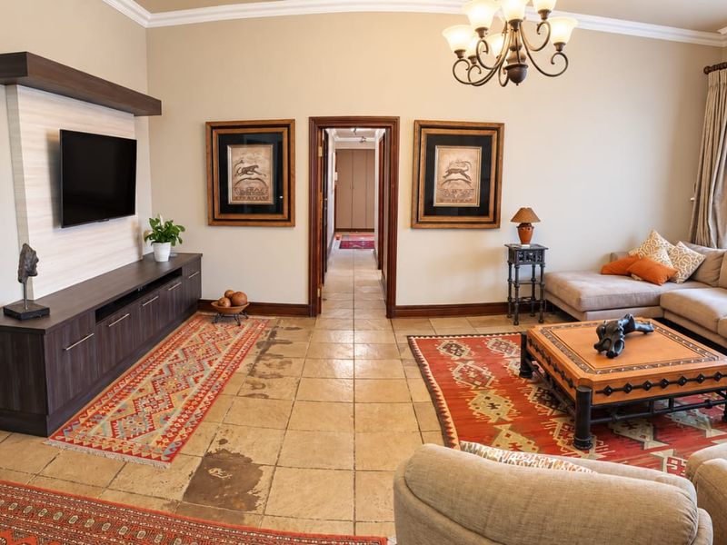 Spacious living room featuring tiled flooring, a built-in media console, and decorative crown molding, providing a comfortable and functional family living space.