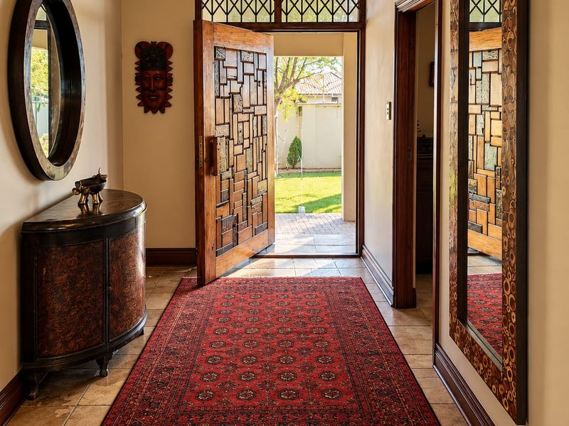 Welcoming entrance hall featuring tiled flooring, a decorative wooden front door with a transom window, and a classic chandelier.