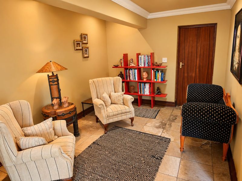A cozy living area featuring stone tile flooring, crown molding, and a solid wooden door, offering a comfortable space for relaxation.