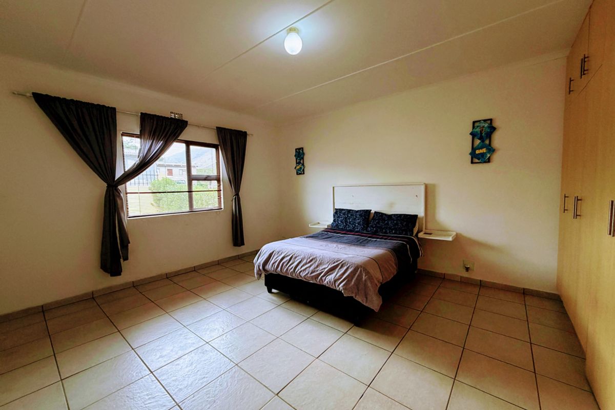 Spacious bedroom featuring neutral tiled flooring, built-in cupboards, and large windows allowing for natural light.