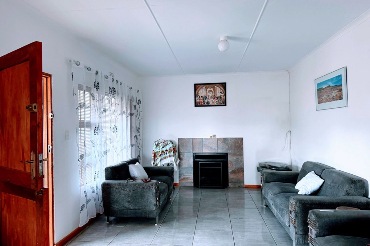 A living room featuring tiled flooring, a built-in fireplace with a stone surround, and direct access through a timber entrance door.