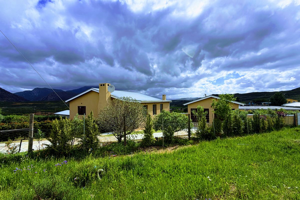 A view of the rear exterior of the house featuring a metal roof, chimney, and surrounding garden area with mountain views.