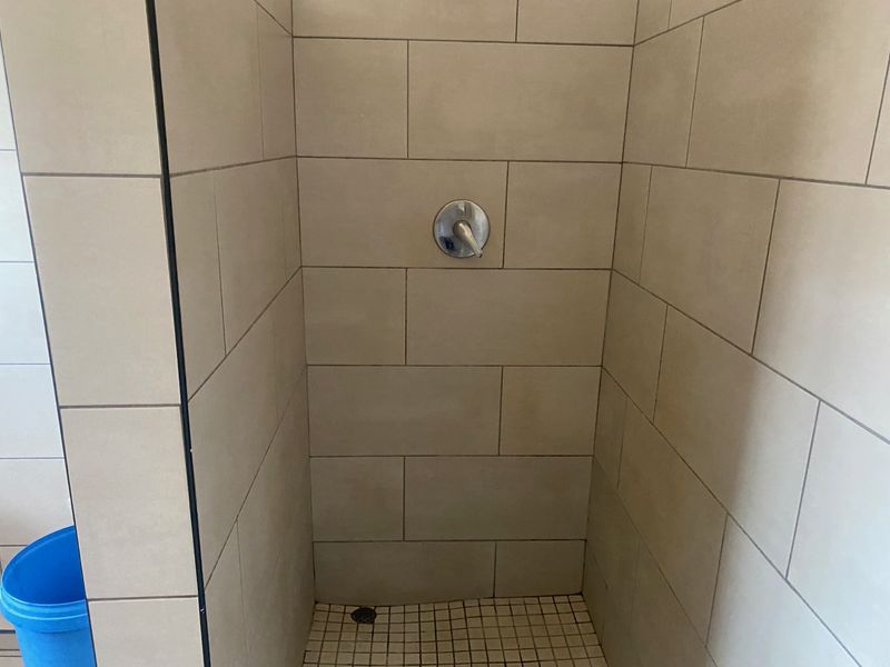 A clean, tiled shower enclosure featuring a modern mixer tap and mosaic floor tiling.