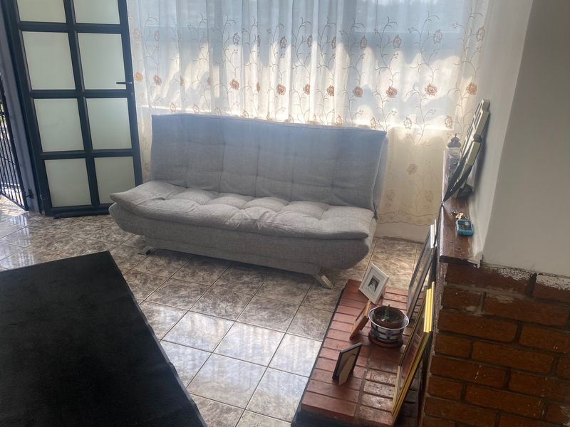 A living area featuring tiled flooring, a brick fireplace, and a framed glass door leading to the exterior.