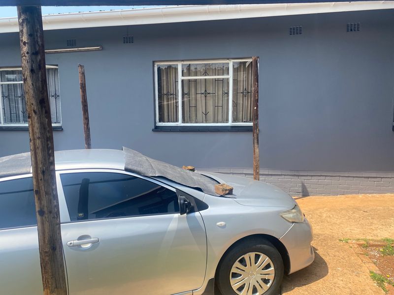 Rear exterior view of the house featuring grey painted walls, white window frames with security bars, and guttering.