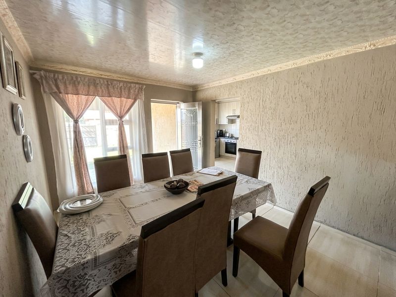 Dining room featuring textured wall finishes, ceiling cornice, and tiled flooring, with an adjacent view into the kitchen area.