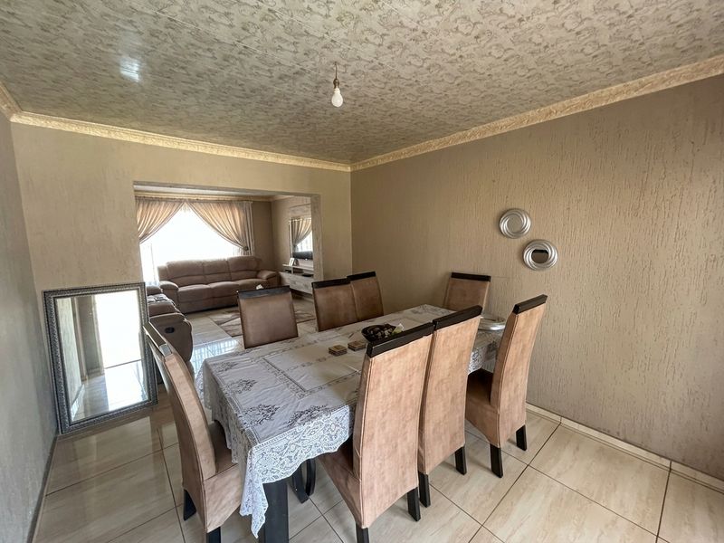 Open plan dining and living area featuring tiled flooring, textured wall finishes, and decorative ceiling molding.