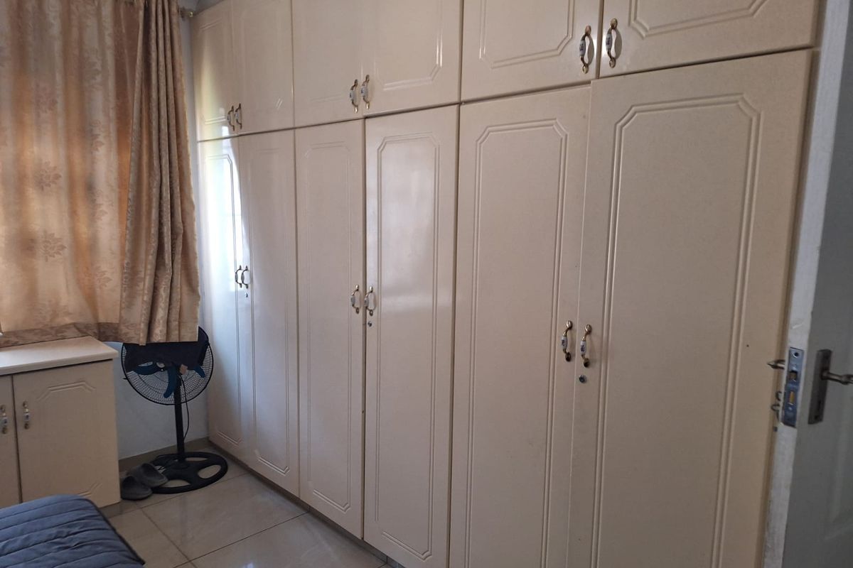 A bedroom featuring extensive floor-to-ceiling built-in cupboards and tiled flooring, providing ample storage space.