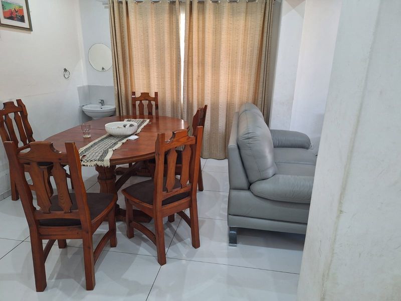 Open plan living and dining area featuring tiled flooring and a convenient wall-mounted basin, offering a functional layout for daily living.