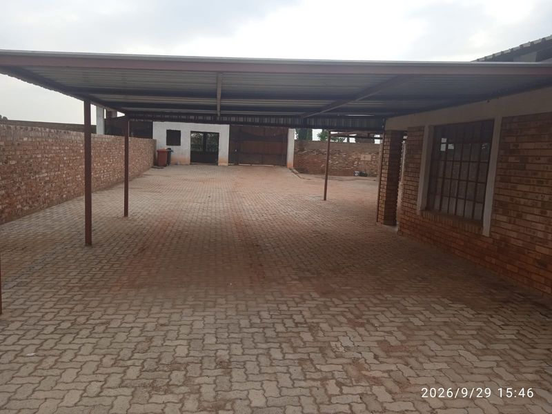 Spacious covered carport area with paved flooring and brick boundary walls, providing ample off-street parking space.