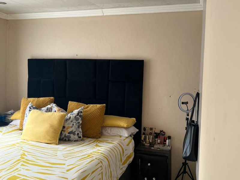 A bedroom featuring tiled flooring and recessed downlights, currently showing signs of wear on the ceiling panels and wall surfaces.